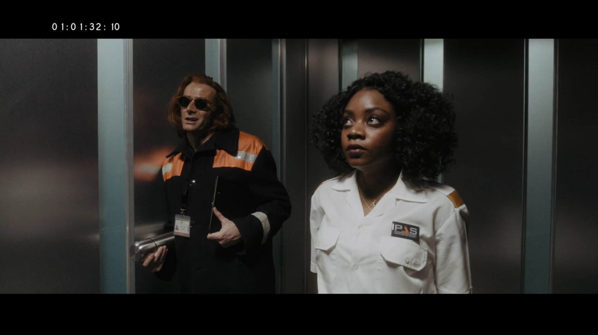 Good Omens deleted scene where Crowley and a cell tower employee ride the elevator up to the control room. Crowley is wearing his signature orange mischief-causing jacket and carrying a stainless steel thermos
