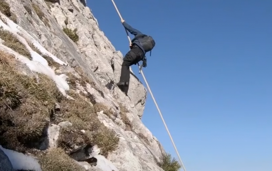 Bear Grylls uses a rope to climb down a gorgeous mountain slope. (Image: National Geographic)
