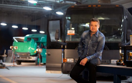 Jeremy Renner stands beside a bus he's remodeling for Disney's Rennervations