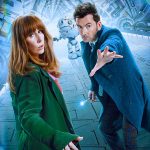 The Fourteenth Doctor and Donna Noble stand on a large mechanical platform. A white robot is visible behind them.