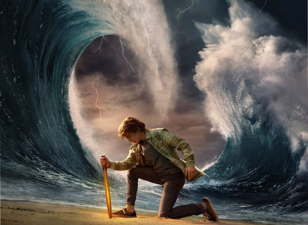 Percy Jackson (Walker Scobell) with a sword in front of an ocean. 