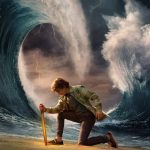 Percy Jackson (Walker Scobell) with a sword in front of an ocean.