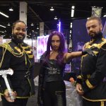 three people (two men and one woman, with the woman in the center) wearing space fantasy type outfits and posing