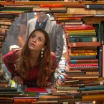 A Wall of books stacked sideways with a hole in the center, out of which a young white woman peers through