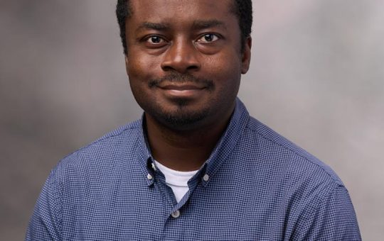 A middle-aged black man wearing a blue shirt.