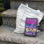 A copy of Chuck Tingle's 2024 release Bury Your Gays sits on a step. Behind it is a bag with a library card design.
