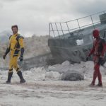 Hugh Jackman as Wolverine (in the yellow suit) and Ryan Reynolds as Deadpool walk across a deserted landscape