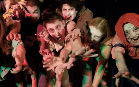 a group of people dressed as zombies, reaching toward the camera