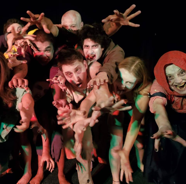 a group of people dressed as zombies, reaching toward the camera