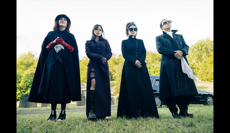 four people - two women, a young lady, and a man - dressed in black and standing on grass