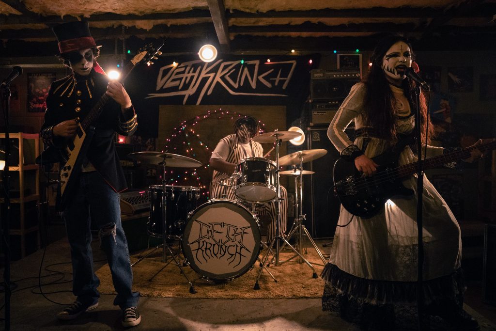 Dylan Cambell (Emjay Anthony), Spud (Kezii Curtis), and Jordy (Chiara Aurelia) dressed in goth/death-style makeup, playing instruments. 