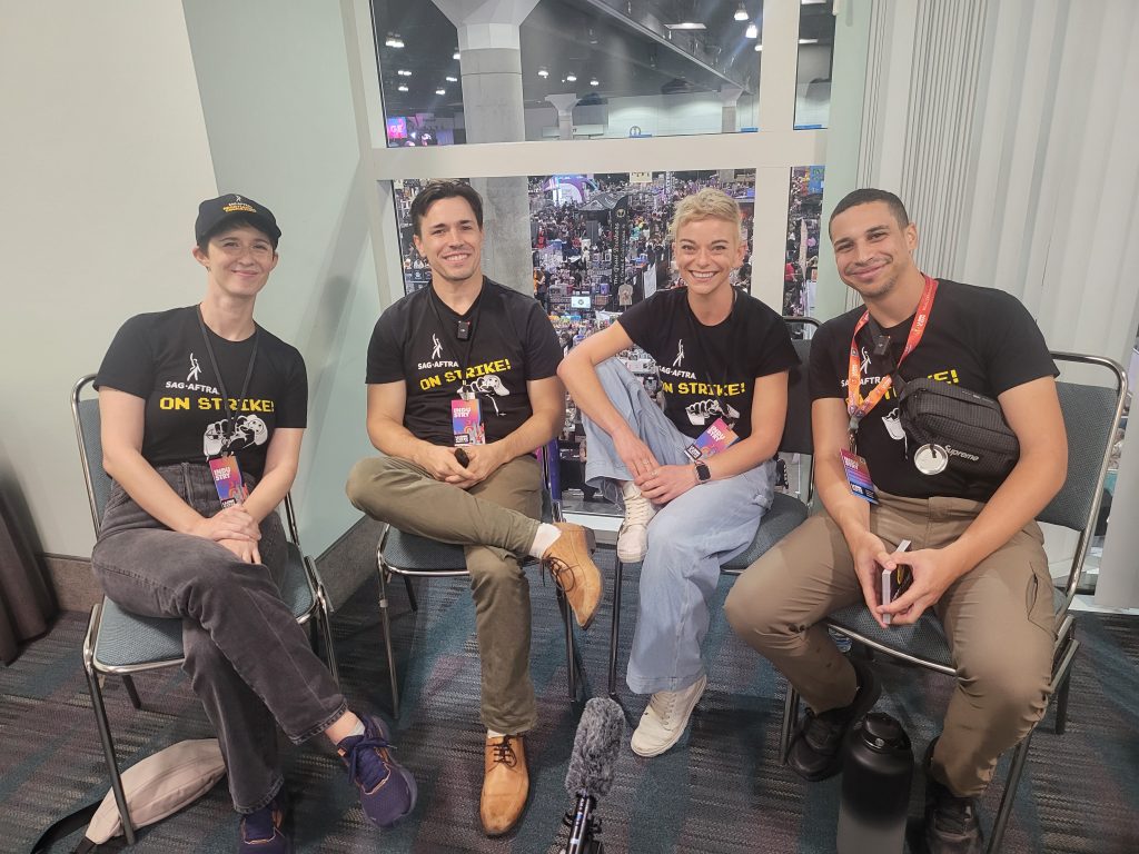 four people - two women and two men - sit on chairs facing the camera