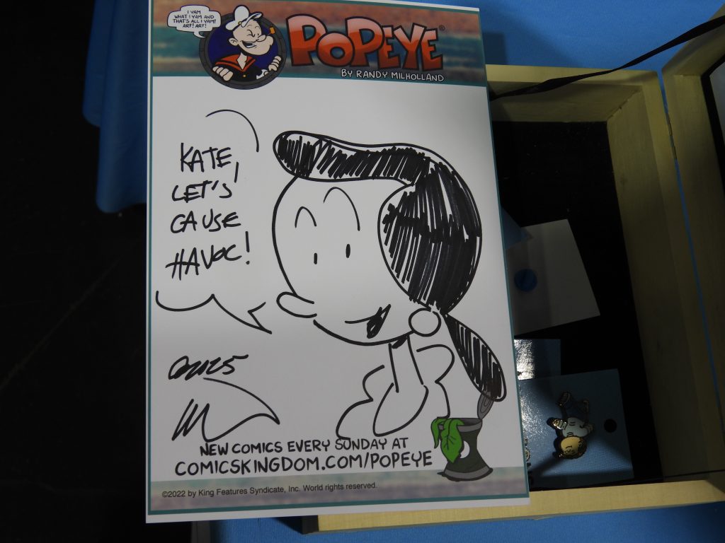 A drawing of Olive Oyl from Popeye, saying 'Kate, let's cause havoc!'