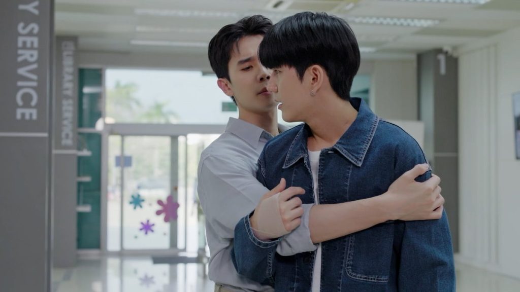 Thap stands slightly behind In, having caught him when he nearly fainted. Thap has his arm around In, and In's arm is bent in a way that he his holding onto Thap's elbow. In is partially turned to Thap, so their faces are very close.