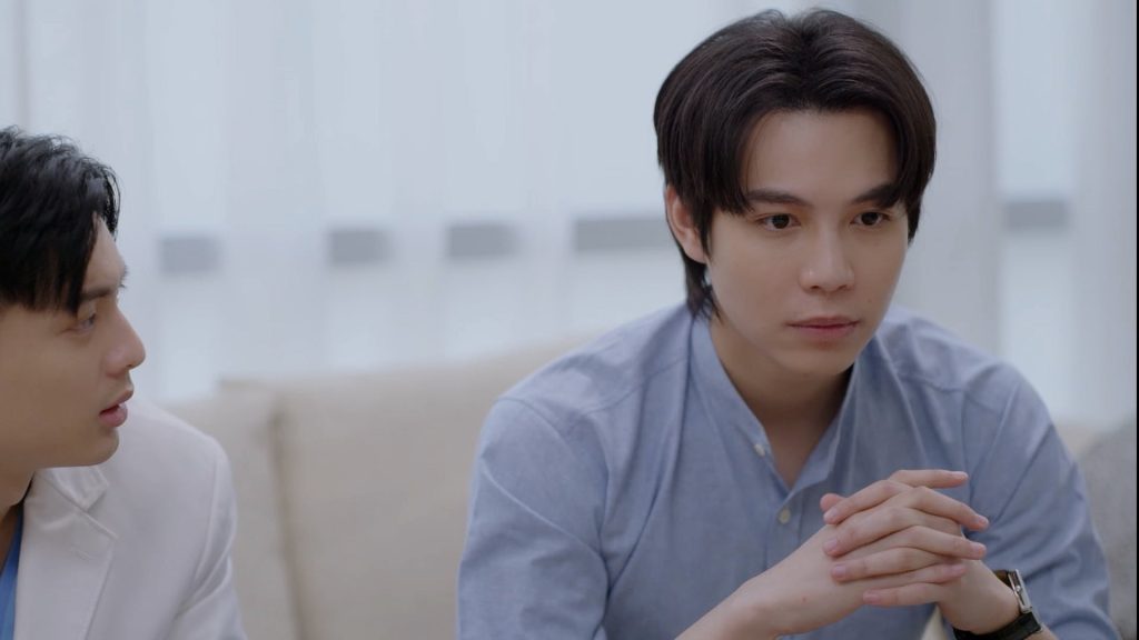 Pong and Karn sit side by side on the couch in Karn's office. While Pong looks at Karn, Karn has his hands folded in front of him and is starting off in the distance.