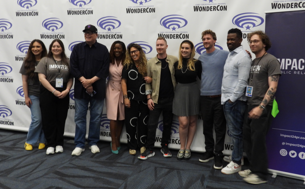 A group of ten people standing in front of the WonderCon backdrop.