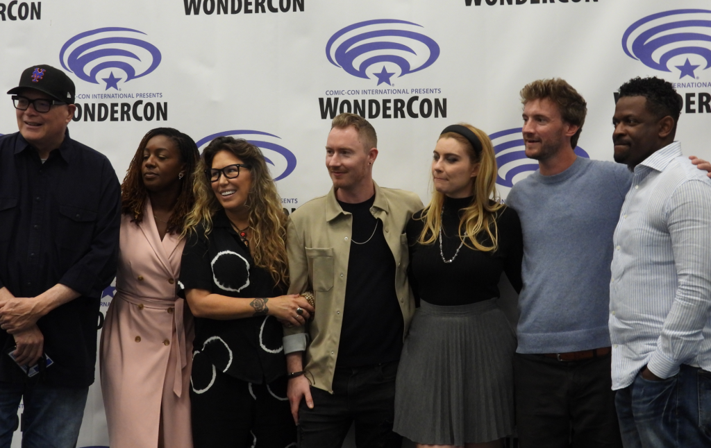 A group of seven people standing in front of the WonderCon backdrop.