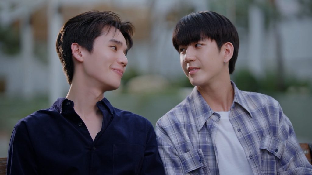 Thap and In sit side by side, gazing at each other and smiling.