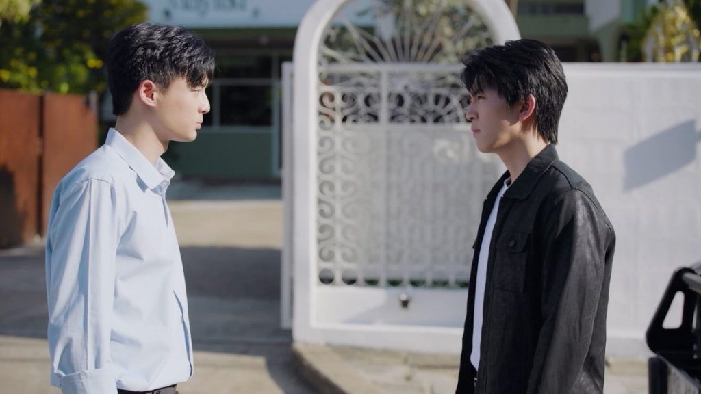 Ton and Pong stand facing each other in front of Ton's car after finding a threatening note on the windshield.