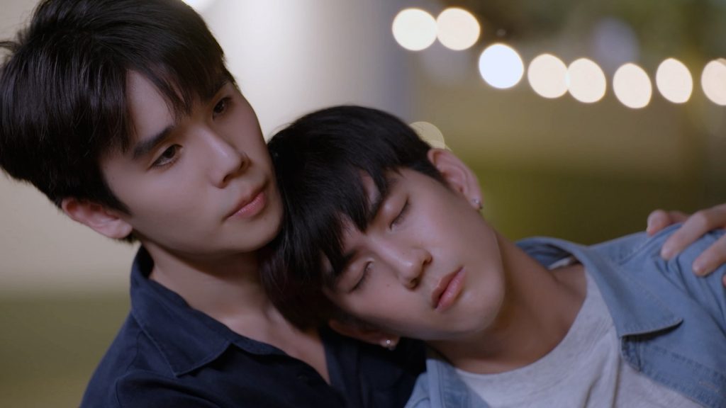 A drunken In has collapsed backwards against Thap, with his head on his shoulder.