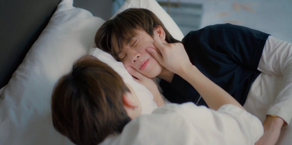 Punn and Ramil lie facing each other in bed. Ramil is pinching Punn's cheeks.