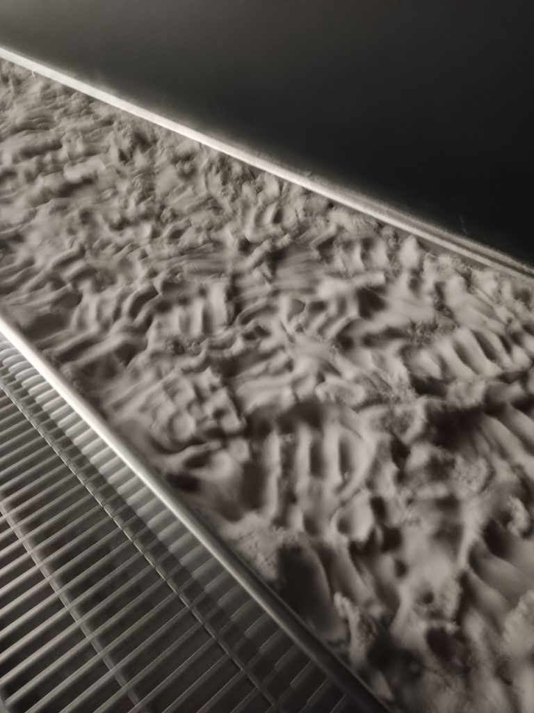 A shelf of kinetic sand. You can see the imprints of people's fingers as they run their hands through the sand.