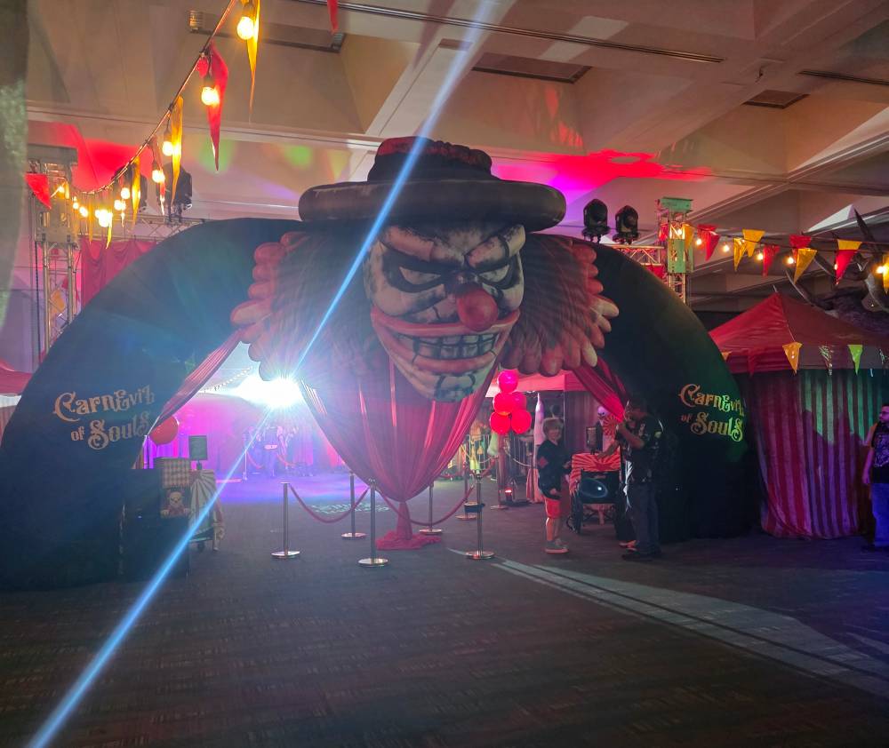 a dark hall with a blowup evil clown over the entrance to a circus
