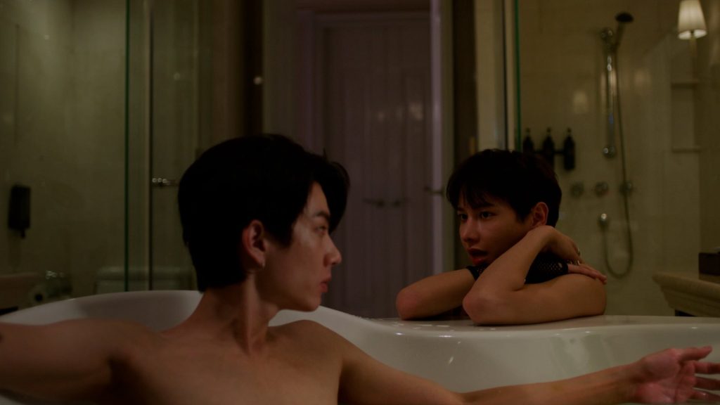 Koh sits in the bathtub. Jira on the floor outside the tub, with his arms leaning on the edge.