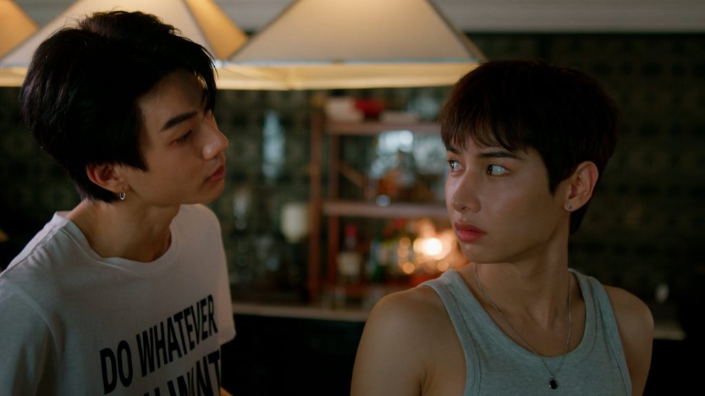 Koh takes Jira's measurements. Jira looks at Koh over his shoulder.