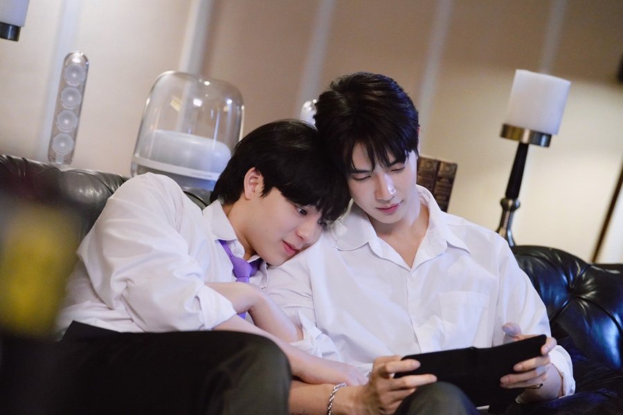 North cuddles up to Johan on the couch. Johan is reading something on his tablet, while North is curled around his arm.