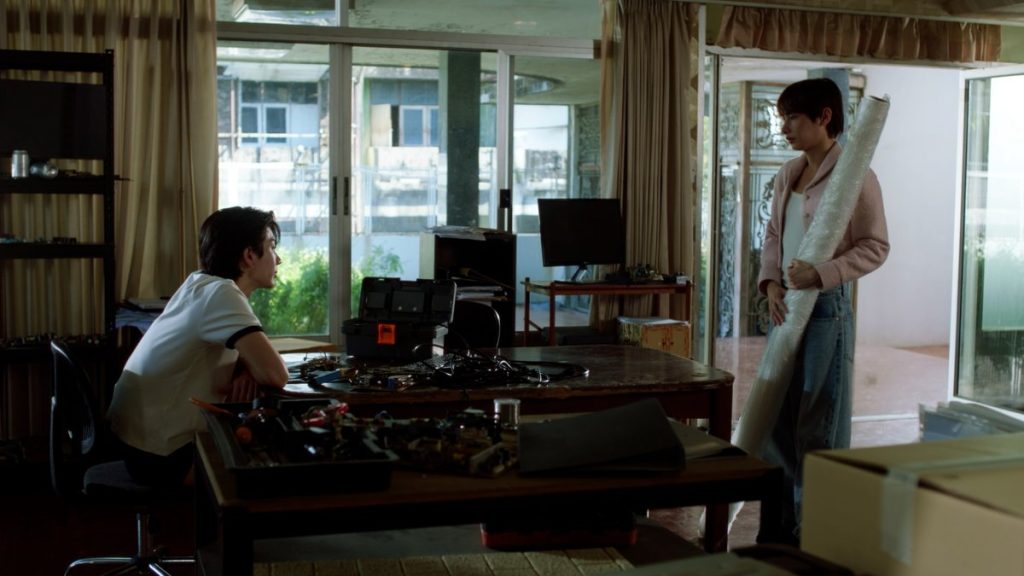 Jira meets Koh at his new apartment in his family's old factory. He is holding the rolled up painting of the two of them that was featured in his exhibition.