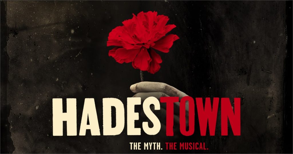 Official Hadestown promotional image: a disembodies hand holding a red cardnation. Text reads: Hadestown, the myth, the musical.