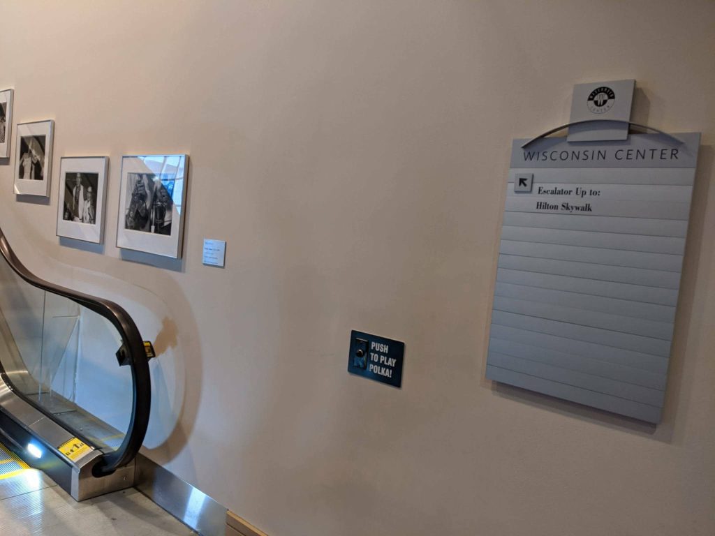 A sign that says "Push Me" next to an escalator. 