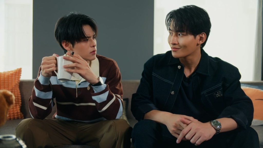 Yu and North side side-by-side on North's sofa. Yu is smiling at North, but North is scowling at Yu.