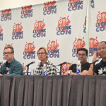 five people sitting at a table, the LA Comic Con logo on banners behind them