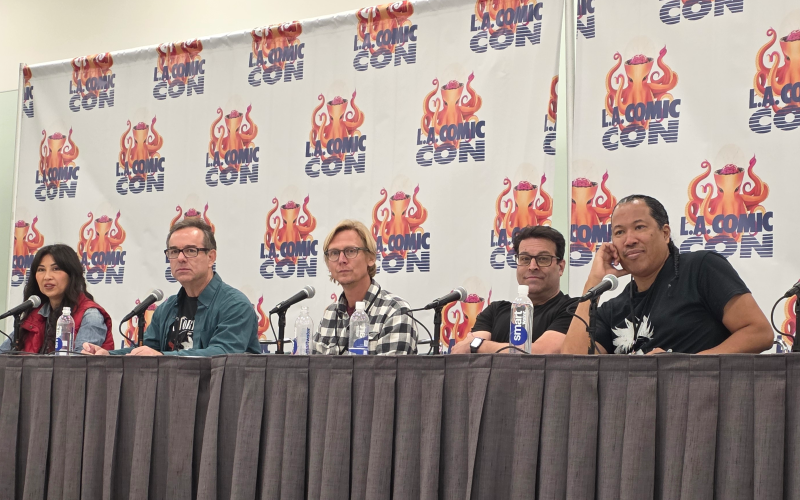 five people sitting at a table, the LA Comic Con logo on banners behind them