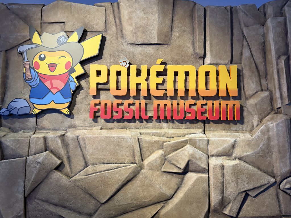 Pokemon fossil museum entrance featuring Pikachu dressed in a tan excavator hat, blue shit, and red handkerchief.