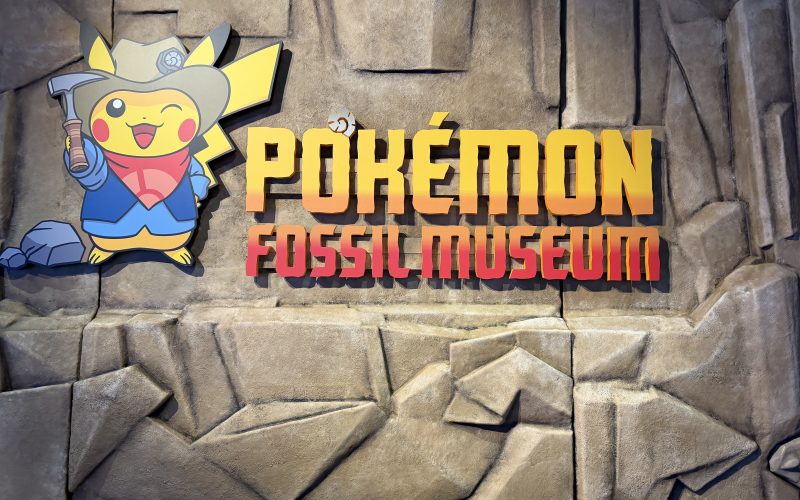 Pokemon fossil museum entrance featuring Pikachu dressed in a tan excavator hat, blue shit, and red handkerchief.